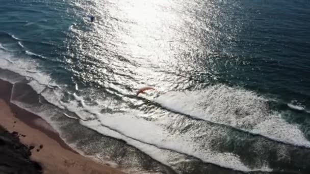 ビーチ崖から広がる自然のビーチまでのパラグライダー活動の空中ビュー — ストック動画