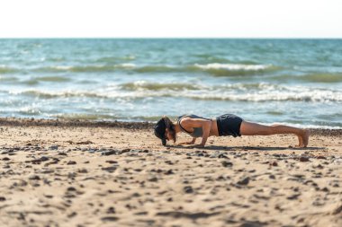 Kumlu plajda tek başına kalasçılık yapan kişi, sakin sahil ortamının ortasında sıkı bir kalas pozisyonunu koruyor.