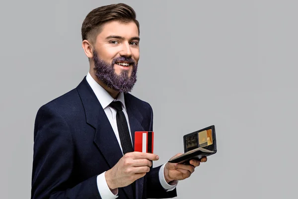 Усміхнений молодий чоловік тримає гаманець і кредитну картку — стокове фото