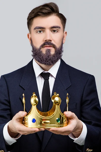 Серйозний бізнесмен тримає золоту корону — стокове фото