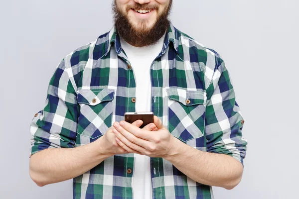 Uomo sorridente con barba che tiene smart phone — Foto Stock