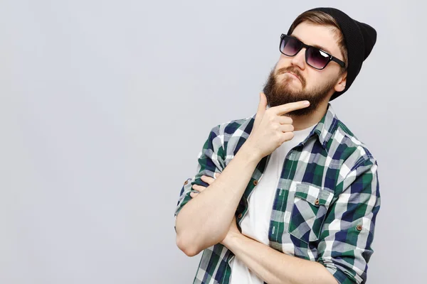 Grappige jonge hipster denken op witte achtergrond — Stockfoto