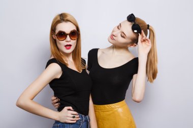 Two female friends at gray studio background