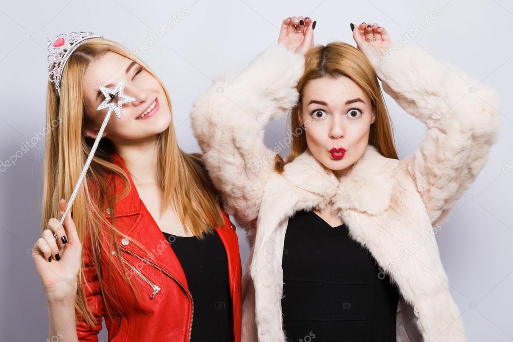 Two female friends at gray studio background