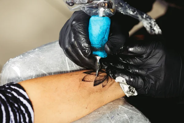 Egy férfi teszi a lótusz virág-tetoválás a fiatal lány karját — Stock Fotó