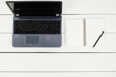 laptop ve açık defter kalem tablo ile