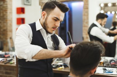 Dark haired barber doing a haircut clipart