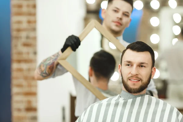 Kapper houdt een spiegel voor client — Stockfoto