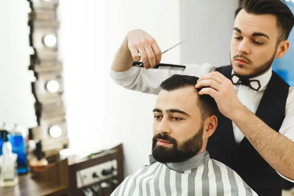 Dark haired barber doing a haircut — Stock Photo, Image