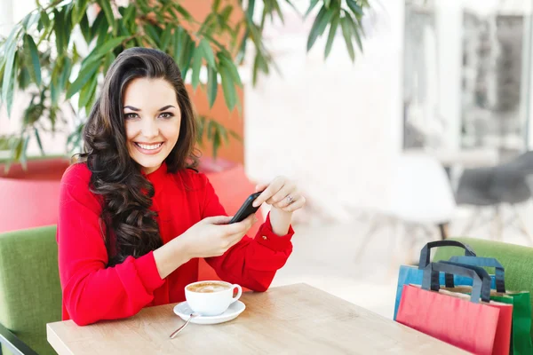 Menina bonita no café no shopping com café e telefone — Fotografia de Stock