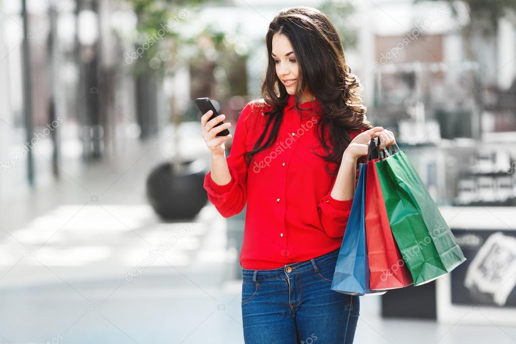 Girl In Mall With Shopping Bags Looking At Phone Stock Photo