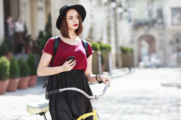 Девушка сидит на велосипеде и держит телефон — стоковое фото