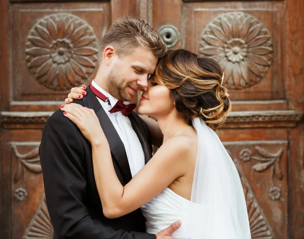 Sposo e sposa abbracciando vicino alla porta di legno — Foto Stock