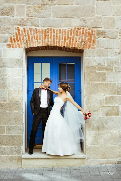 Married couple standing near blue door