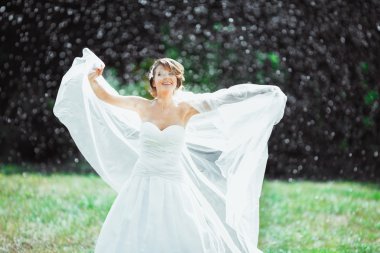 Yağmur altında duran gelin gülümseyen