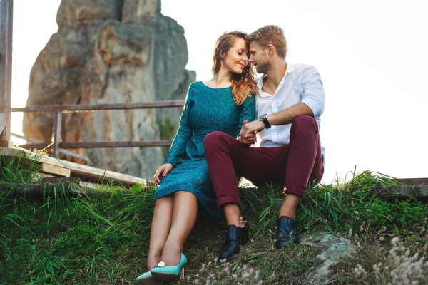 Nice couple sitting on grass near rock — Stock Photo, Image