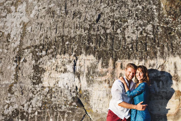 Feliz abraçando casal sorridente perto da parede de pedra — Fotografia de Stock