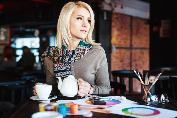 Chica sentada en la cafetería con taza de té y dibujos —  Fotos de Stock