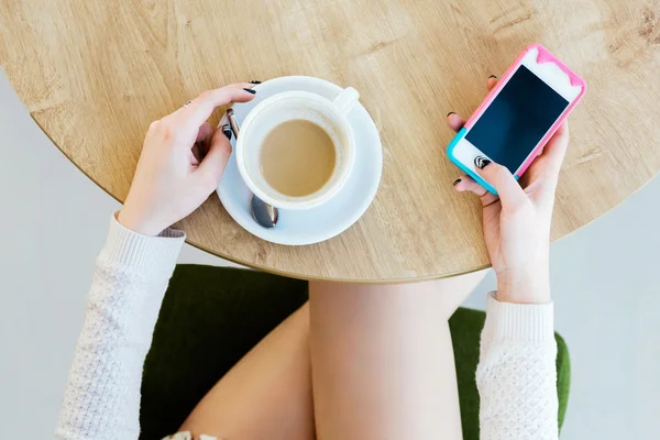 Pernas de menina, xícara de café e telefone celular — Fotografia de Stock