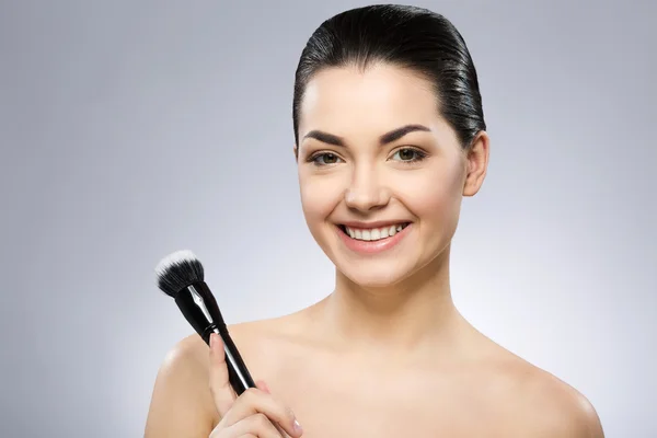 Sonriente chica sosteniendo maquillaje cepillo — Foto de Stock