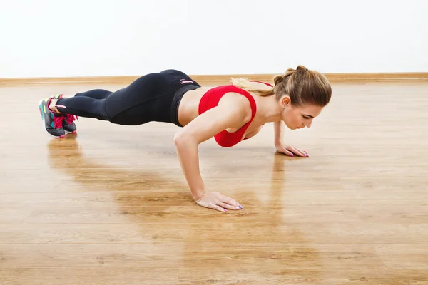 Chica atractiva en forma haciendo ejercicios físicos en el gimnasio — Foto de Stock