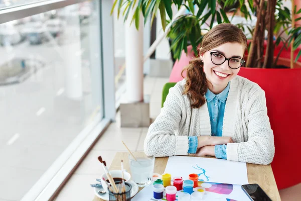 Chica con gafas sentado con pinturas de colores — Foto de Stock
