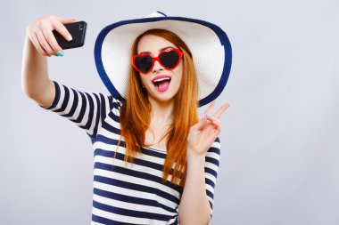 Şapkalı ve güneş gözlüklü kız selfie yapıyor