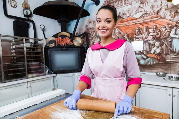 Молодая улыбающаяся женщина разминает тесто — стоковое фото