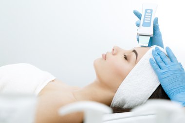 Doktor yüz ultrasonik temizlik prosedürü yapıyor