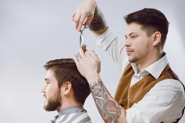 Attractive barber doing a haircut — Stock Photo, Image