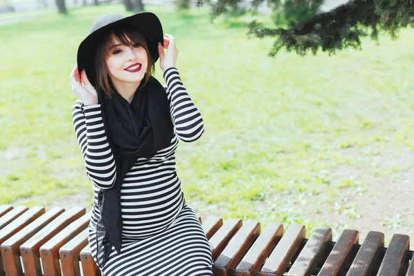 Pregnant woman sitting on bench and smiling — Stock Photo, Image