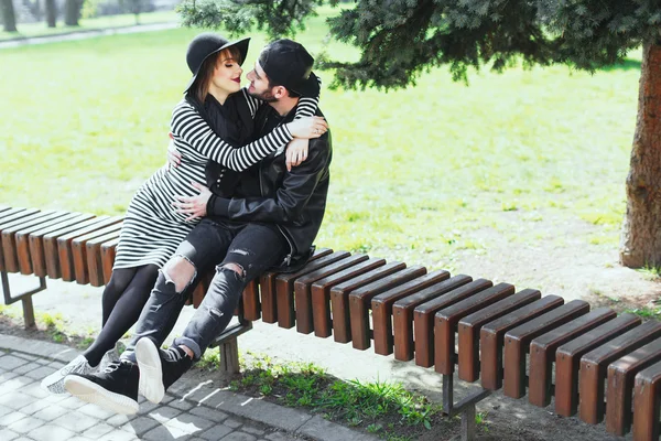 Man och gravid kvinna som sitter på bänken — Stockfoto