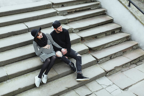 Pregnant girl and man sitting on stairs