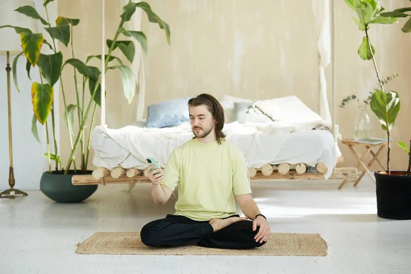 Красивый Человек Сидит Циновке Yoga Используя Телефон Учитель Yoga Дома — стоковое фото