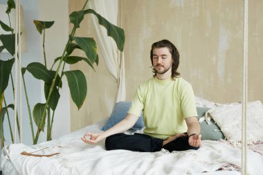 Evde yakışıklı yoga hocasıyla Zen antrenmanı. Uzun saçlı harika bir meditasyon ustası. Evde konsantrasyon çalışması yapıyor.