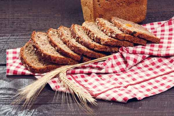 Кусочки хлеба с шипом пшеницы на ткани на досках — стоковое фото