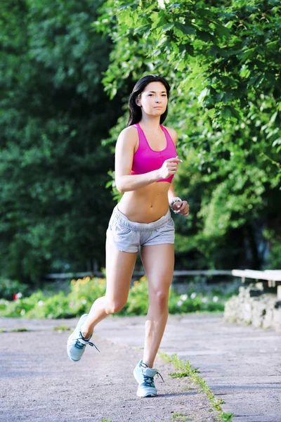 Brunette woman, jogging in the green park — стокове фото