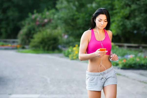 Mujer corriendo en el parque, escuchando música en el teléfono inteligente — Foto de Stock