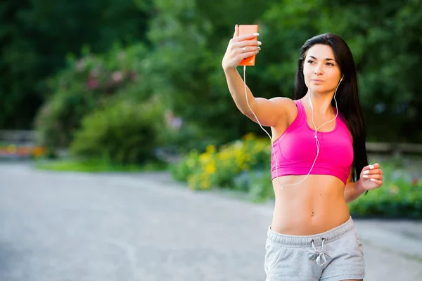 Chica atlética, tomando selfie, escuchando música con auriculares — Foto de Stock