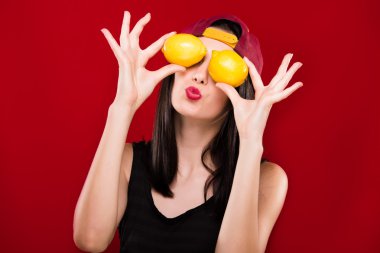 Pretty woman holding two oranges in front of her face