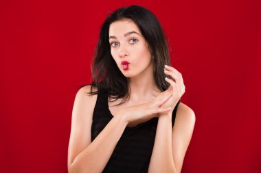 Pretty young girl having fun on red background, in studio