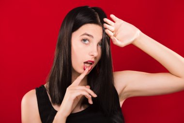 Passionate brunette woman posing on the red background in studio