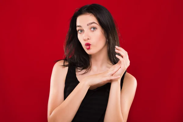 Hübsches junges Mädchen hat Spaß auf rotem Hintergrund, im Studio — Stockfoto