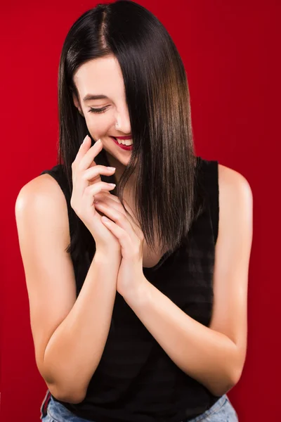 Gorgeous young woman standing on the red background and laughing — Stock Photo, Image