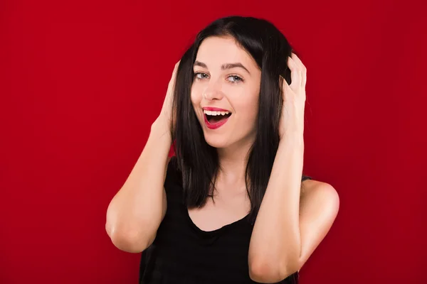 Cute young woman posing on the red background and laughing — Stock fotografie