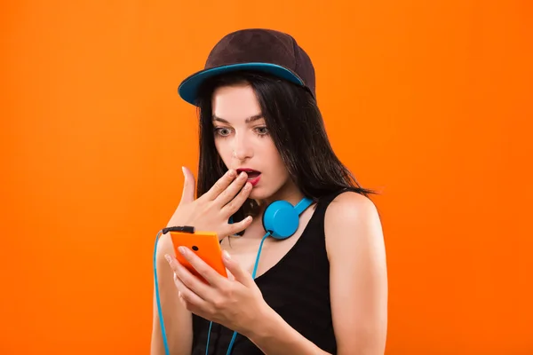 Surprised young brunette woman holding smart phone in her hand — Zdjęcie stockowe