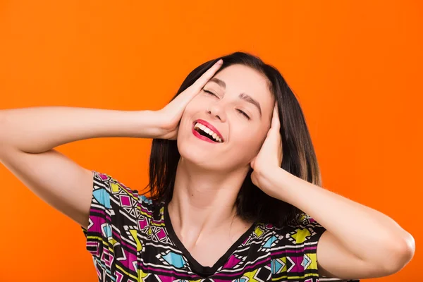 Schöne lächelnde junge Frau posiert auf dem orangefarbenen Hintergrund — Stockfoto