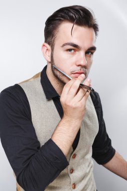 Jilet yüzüne yakın tutan genç Kuaför