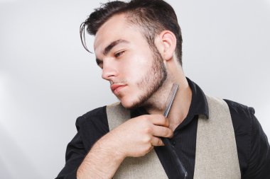 Esmer Kuaför yüzünü yakınındaki ustura ile poz