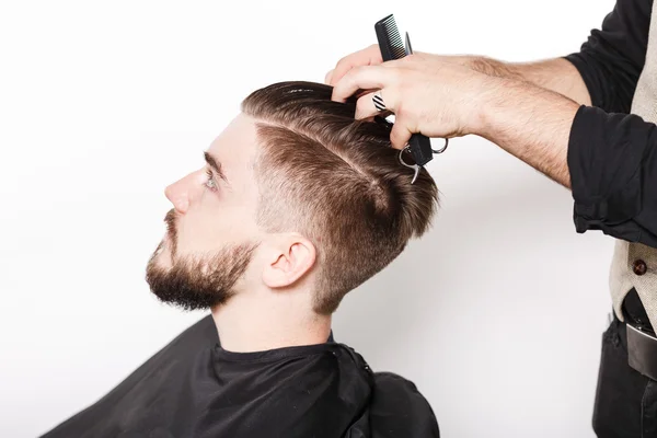 Парикмахер бреет молодого человека — стоковое фото